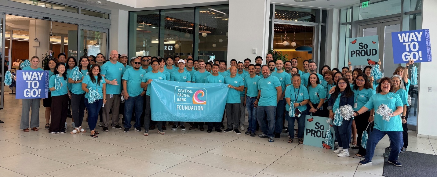 Central Pacific Bank Foundation employees gather with signs and a foundation banner before participating in a community march supporting domestic violence awareness and prevention.