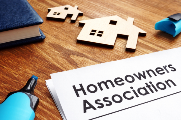 Close-up of a document labeled "Homeowners Association" beside wooden house models, representing HOA information or homeownership.