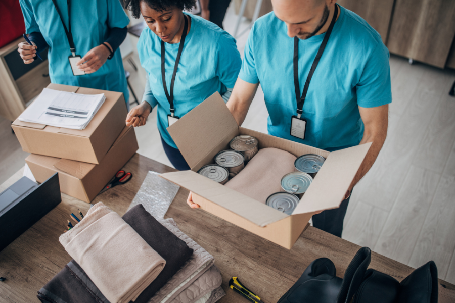 CPB volunteers working together to pack boxes with food and essential items for a charitable donation or relief effort.