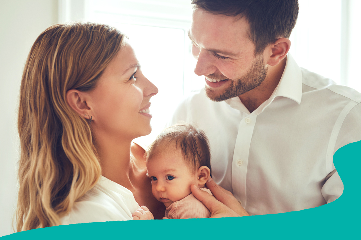 Two smiling parents holding their baby.