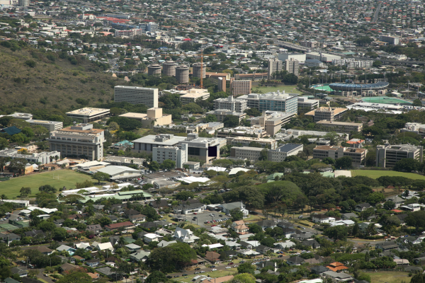 Elevated view of the University of Hawaiʻi at Mānoa campus, showing academic buildings, athletic facilities, nearby neighborhoods, and the surrounding Honolulu landscape.