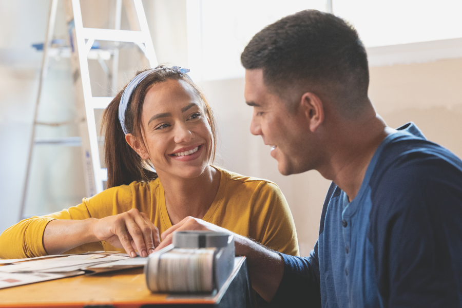 Smiling couple discussing renovation ideas and reviewing design samples while planning improvements to their home.