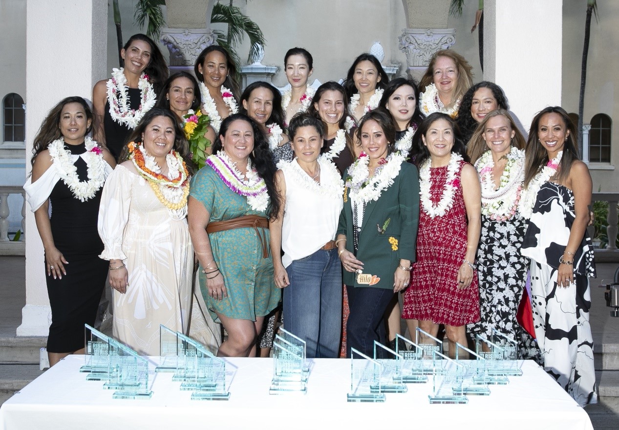 Members of the WE by CPB Rising Tide cohort gather for a commemorative group photo with achievement awards displayed in front of them at a program celebration.