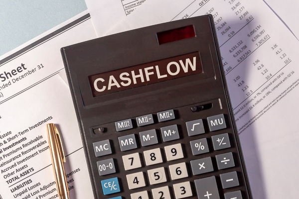 Close-up of a calculator labeled "Cashflow" on top of financial statements and reports, representing budgeting, cash flow management, and financial planning.
